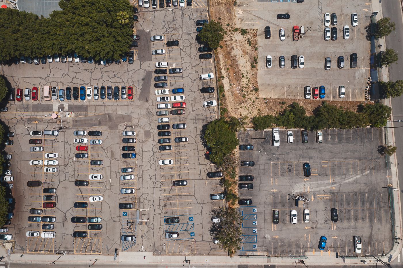 Aerial view of an urban parking lot with rows of cars